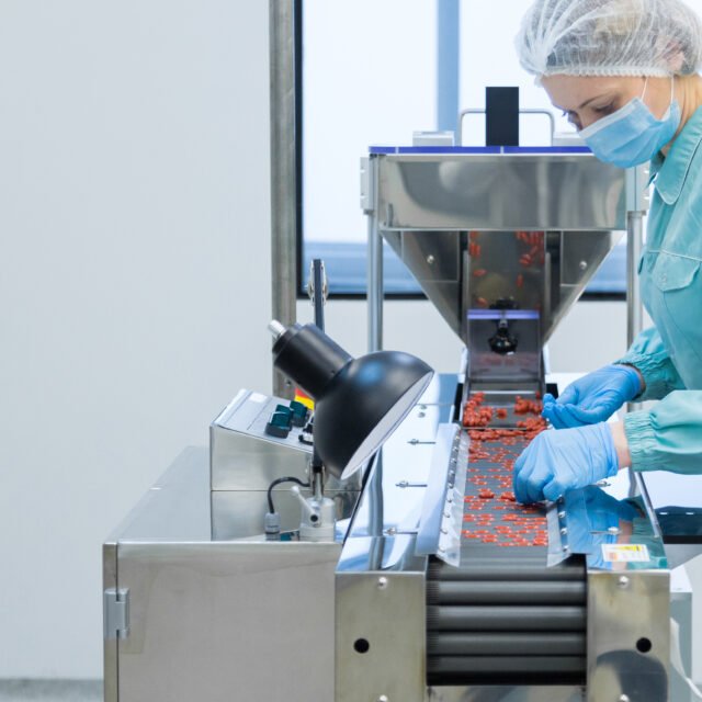 Pharmaceutical technician in sterile environment working on production of pills at pharmacy factory